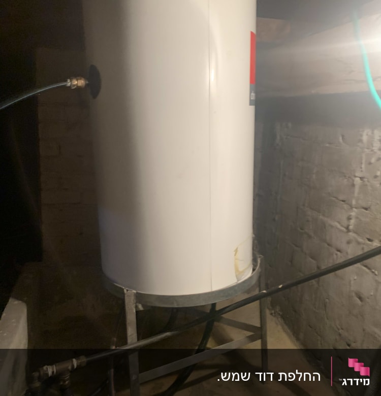 דוד שמש לבן עם צינורות מחוברים במרתף